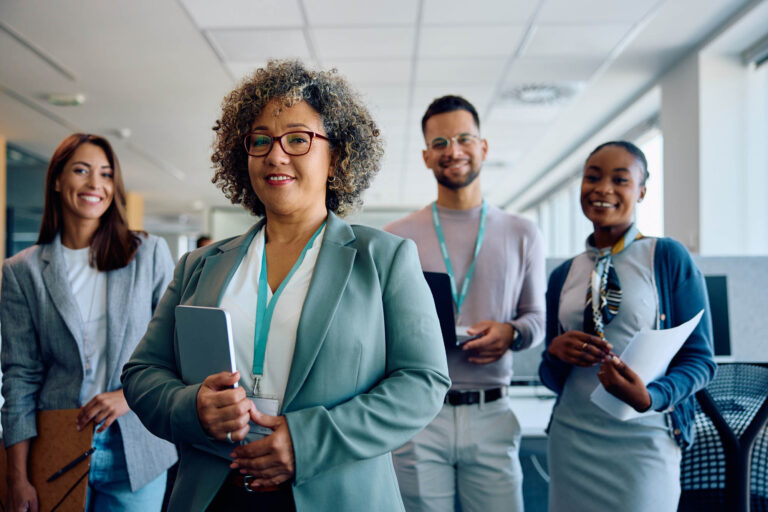 Mature leader and her case management business team in the office looking at camera. | Healnex