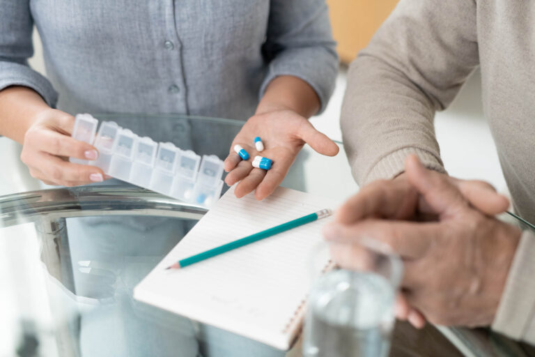 Hands of young woman holding pills while showing medicine to sick senior father | Healnex