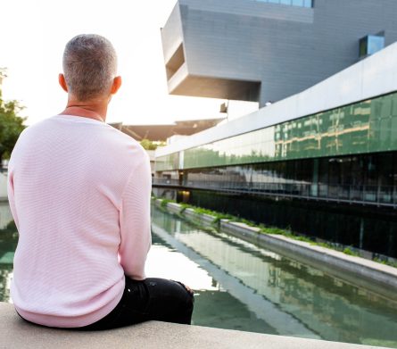 Caucasian man with pink sweater looking to a serene modern city | Healnex